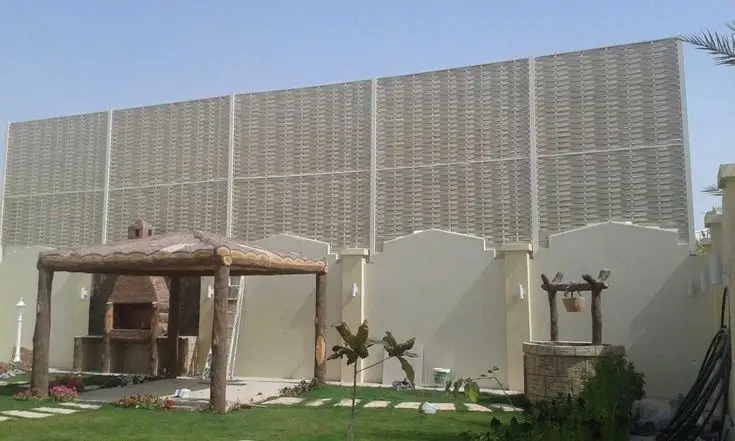 صورة لسياج حديقة خارجي طويل مصنوع من ألواح بتصميم منسوج باللون البيج ومُثبت على جدار خارجي، مع وجود مظلة خشبية